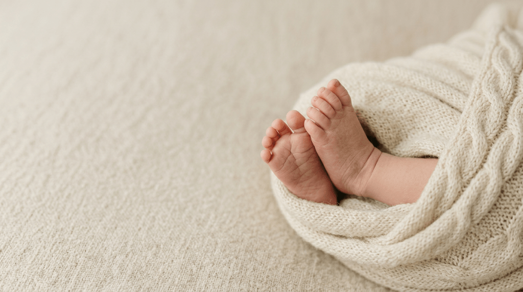 Newborn baby's feet wrapped in beige blanket 